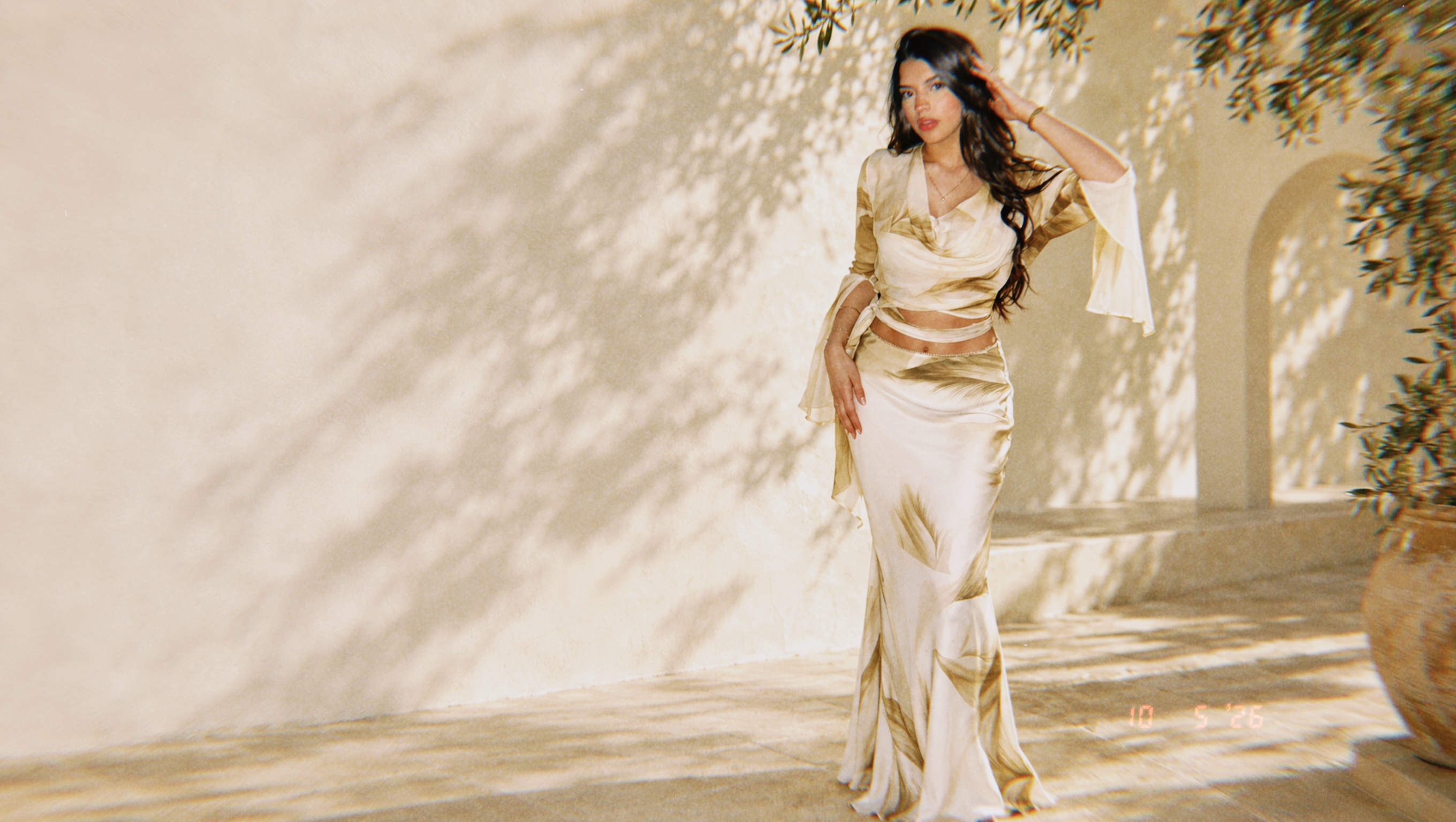Mia Flores con el conjunto de satén marfil y dorado, en una escena de verano